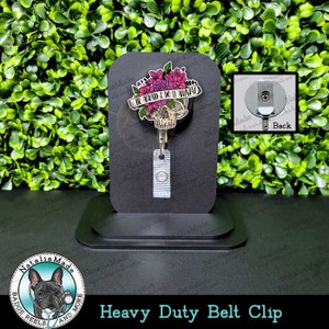 May include: A black heavy duty belt clip with a skull and floral design. The skull has a pink and black banner that reads "Be Afraid & Do It Anyway".