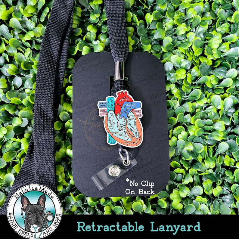 May include: A retractable lanyard with a black strap and a badge reel featuring a colorful anatomical heart design. The badge reel has the text "Natalia Made" and "Retractable Lanyard". The text "*No Clip On Back" is also visible.