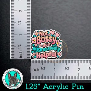 May include: A 1.25 inch acrylic pin with pink and blue flowers and the text "Not Bossy Just Aggressively Helpful".