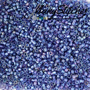 May include: A close-up image of a large quantity of small, round, iridescent blue glass beads. The beads have a metallic sheen and are perfect for jewelry making or other craft projects.