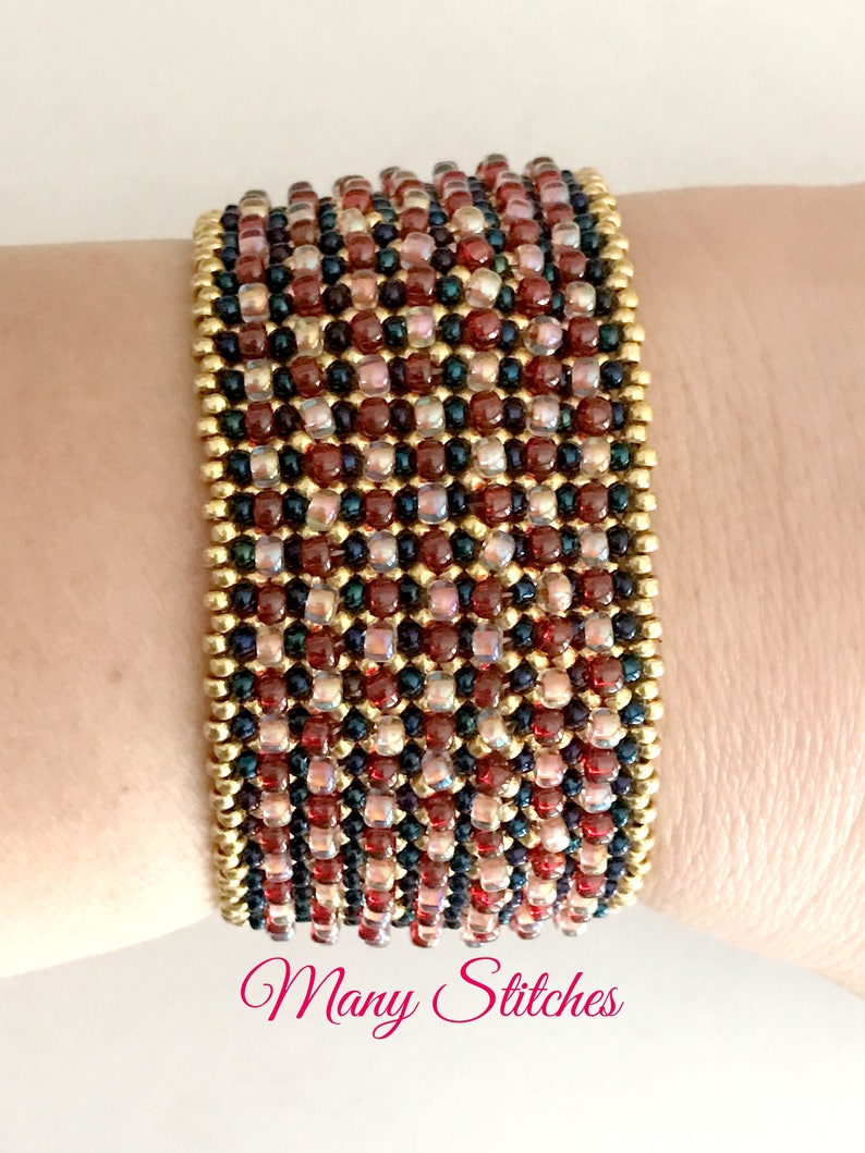K&ouml;nnte beinhalten: Ein mehrfarbiges Perlenarmband mit goldenen Akzenten. Das Armband besteht aus kleinen, runden Perlen in Rot-, Braun- und Schwarzt&ouml;nen. Das Armband wird am Handgelenk einer Person getragen.