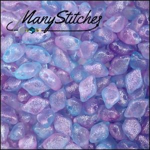 May include: Close-up of a collection of iridescent glass beads in shades of purple, blue, and pink. The beads have a textured, glittery appearance. The words "Many Stitches" are written in cursive across the top.