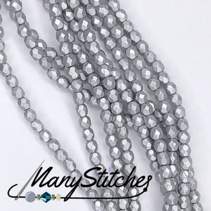 Puede incluir: Una hebra de cuentas de vidrio facetadas de color plateado. Las cuentas son pequeñas y tienen una forma ligeramente irregular.
