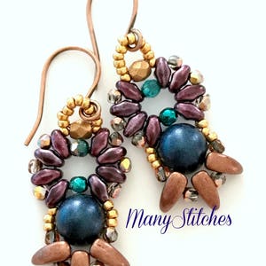May include: A pair of dangle earrings with a copper wire hook, featuring a circular design of purple, gold, and green beads with a dark blue round bead in the centre. The earrings are labelled "Many Stitches" and "484-EOD-B".