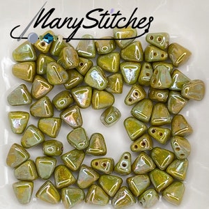 May include: A group of approximately 40 small, triangular, green glass beads with iridescent accents. The beads have three holes each.