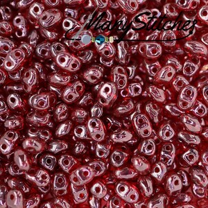 May include: A close-up image of a pile of small, red, glass beads. The beads are shaped like teardrops with two holes at the top. The beads have a shiny, iridescent finish.