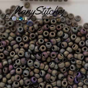May include: A close-up image of a pile of small, round, iridescent beads. The beads are a mix of brown, purple, and gray colors. The beads are all the same size and shape.