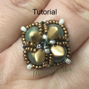 Könnte beinhalten: Ein goldener und grüner Perlenring mit einem Blumenmuster. Der Ring befindet sich an einem Finger und das Wort "Tutorial" steht über dem Ring.