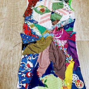 May include: A colorful patchwork quilt made from scraps of fabric in various patterns and colors, including red, blue, green, yellow, and pink. The quilt is stitched together with a variety of stitches and has a rustic, handmade look.