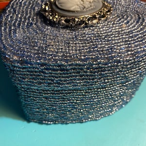 Joyero de cartón con forma de corazón cubierto de pequeños diamantes de imitación y un camafeo en la tapa.