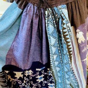 May include: A blue and black patchwork skirt with a geometric pattern. The skirt has a drawstring waist and is made of a soft, comfortable fabric.