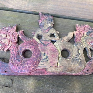 Vintage Indonesian architecture art. Carved board with dragon and human figures.