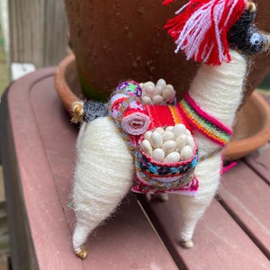 Llama with fringed Peruvian saddle and beadwork. Peruvian folk art. Folk art.