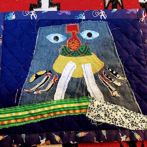 Fabric art with prominent traditional guardian motif and vibrant cowboy collage backing. Mini quilt. Place mat. Boro embroidery.