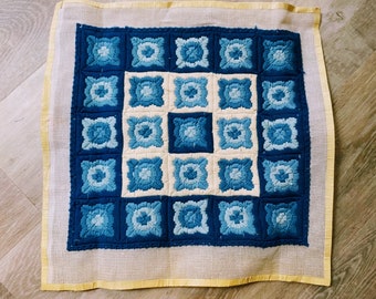 May include: A blue and white needlepoint canvas with a geometric pattern of squares. The squares are filled with a variety of blue shades and white.