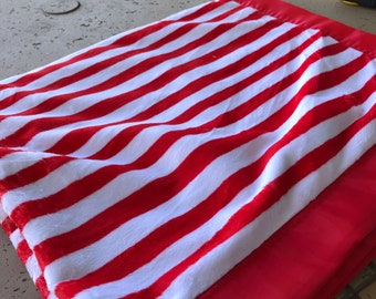 A  red and white Dr. Seuss stripe design minky blanket , red and white,it has a red satin binding around it.