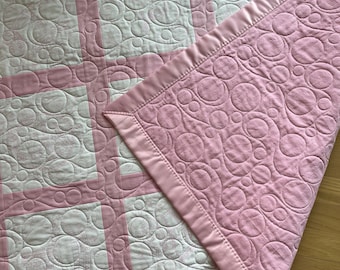 An embroidered pink and white quilt