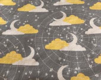 A yellow, gray and white moon and clouds flannel print in the back a gray star MInky