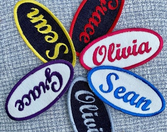 Puede incluir: Seis parches de tela ovalados con nombres bordados. Los nombres son "Sean", "Grace", "Olivia" y "Sean". Los parches son de varios colores, incluyendo amarillo, rojo, morado, azul y negro.