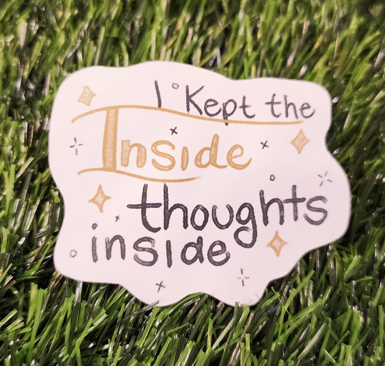 May include: A white sticker with the text "I kept the inside thoughts inside" in black and gold lettering. The sticker has a unique shape and is decorated with small star and diamond shapes.