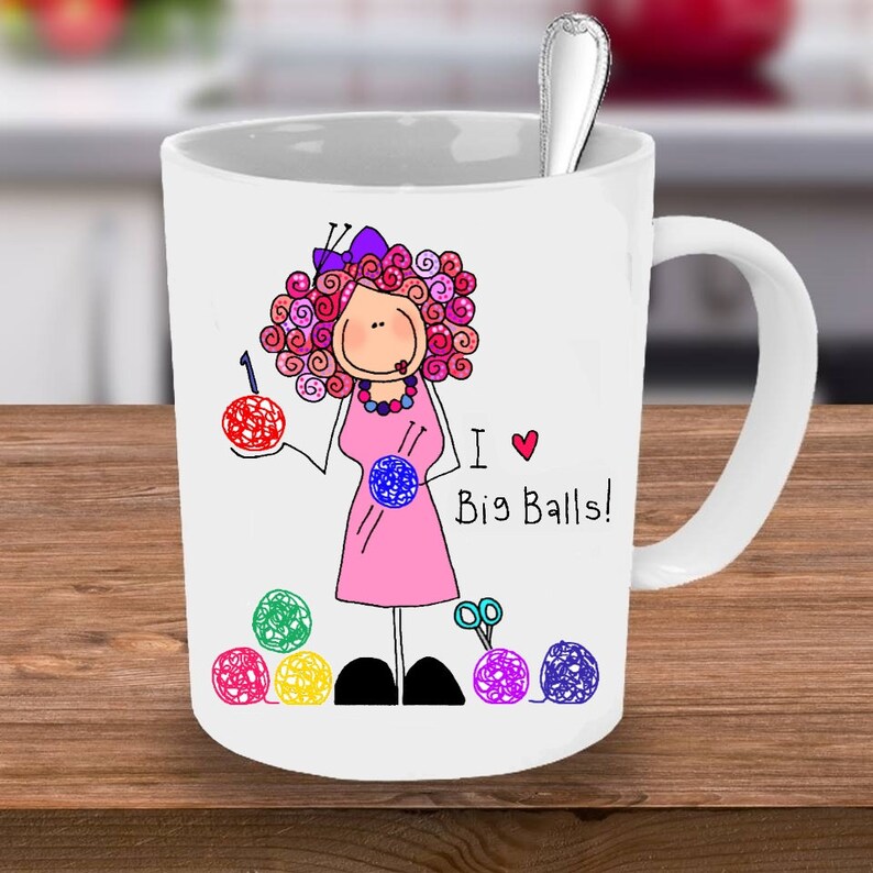 May include: White ceramic mug with a cartoon illustration of a woman holding yarn balls and knitting needles. The text "I &hearts; Big Balls!" is printed on the mug.