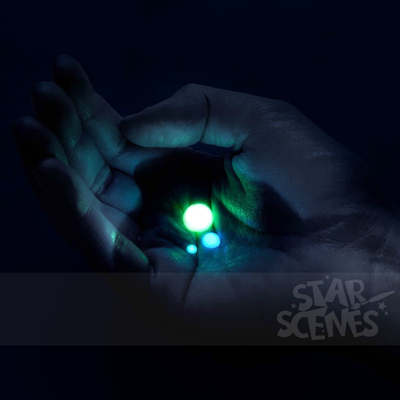 May include: A hand cupped around a glowing green orb, with smaller, fainter orbs surrounding it. The background is dark.