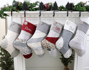 Pode incluir: Seis meias de Natal acolchoadas em vários padrões e cores, penduradas numa lareira. Cada meia tem uma punho cinzento e um pendente de floco de neve. Algumas meias são bordadas com nomes como "Mãe", "Lucy" e "Pai".