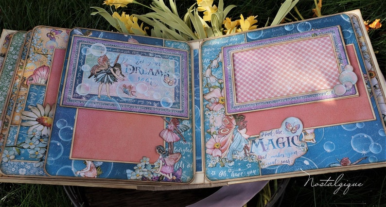 K&ouml;nnte beinhalten: Eine Scrapbook-Seite mit blauem und rosa Farbschema, die Feen, Blasen und den Text "Lass deine Tr&auml;ume fliegen" und "Finde die Magie, die deine Seele zum Leuchten bringt" zeigt.