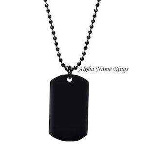 May include: A black dog tag necklace with a black ball chain. The dog tag is blank and has a rounded rectangular shape.