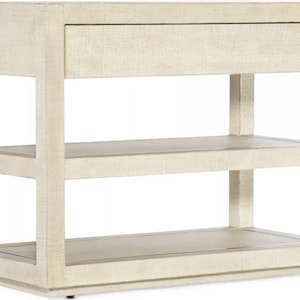 May include: Off-white wooden side table with a single drawer and two open shelves. The table has a rectangular shape with a textured finish. The design is modern and minimalist, suitable for various home decor styles.