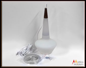 May include: White frosted glass pendant light with a brown wooden top. The light is hanging from a white cord and has a white plug.