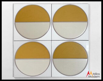 May include: Four square tiles with a mid-century modern design. Each tile features a circle divided horizontally, with the top half in mustard yellow and the bottom half in off-white. The tiles are bordered in a thin gray line.