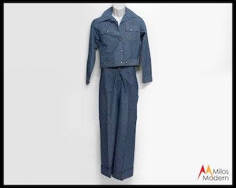 May include: A blue denim jacket and matching pants. The jacket has a button-up front and a pointed collar. The pants have a straight leg and a cuffed hem.