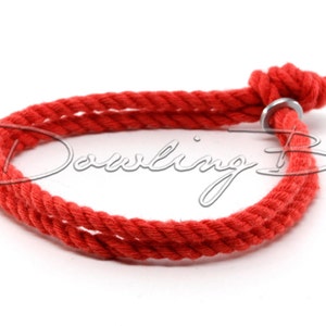 May include: A red cotton rope bracelet with a silver metal ring closure.