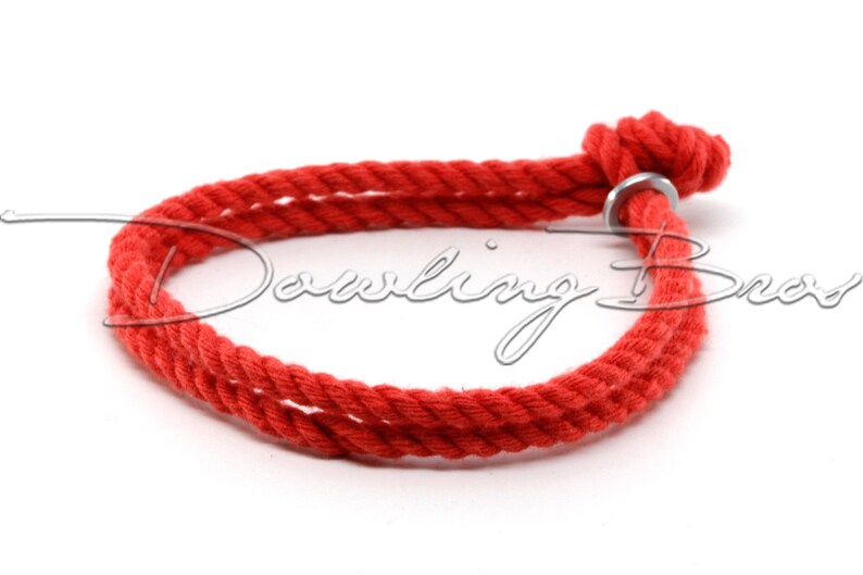 May include: A red cotton rope bracelet with a silver metal ring closure.