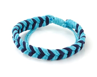 Op de afbeelding: Een blauw en donkerblauw gevlochten armband. De armband is gemaakt van geweven koord en is met een knoop vastgemaakt.