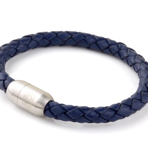 May include: A navy blue leather bracelet with a braided design and a silver magnetic clasp.