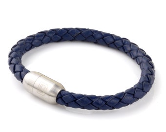 May include: A navy blue leather bracelet with a braided design and a silver magnetic clasp.