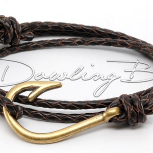 Op de afbeelding: Een bruin leren gevlochten armband met een gouden vishaak sluiting.