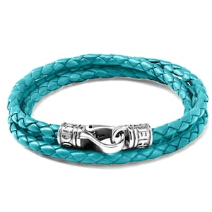 May include: A turquoise leather bracelet with a silver clasp. The clasp has the word "SEEH" engraved on one side and "GOD" engraved on the other side.