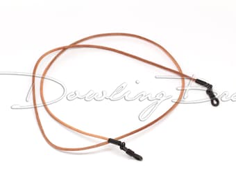 Peut inclure: Une chaîne de lunettes en cuir marron avec des fermoirs en métal noir. La chaîne est bouclée et prête à être portée.