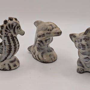 May include: A set of three ceramic mugs with a speckled, matte finish. The mugs are in shades of cream, light gray, and dark gray. Each mug has a simple, minimalist design, perfect for coffee or tea.