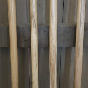 May include: Four unfinished wooden dowels of varying lengths, arranged vertically against a wooden background. The dowels are light brown with visible wood grain. The ends are rounded. Ideal for craft projects.