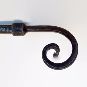 May include: A black metal curtain rod finial with a spiral design.