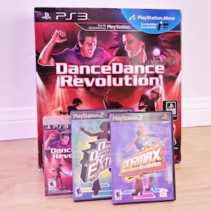 Puede incluir: Una colección de cajas de videojuegos Dance Dance Revolution para PS3 y PlayStation 2. La caja principal presenta el título del juego en letras rojas grandes con imágenes de personas bailando. Se ven cajas de juegos adicionales.