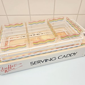 May include: A vintage serving caddy with three clear rectangular dishes. The dishes and the box are decorated with colorful wavy lines. The box reads "SERVING CADDY" and "Buffet Ware". The caddy has a white metal frame.