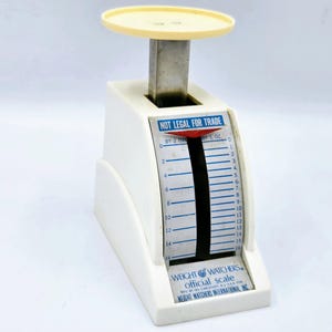 Puede incluir: Una báscula oficial Weight Watchers vintage. La báscula de plástico blanco tiene una plataforma amarilla y un poste de metal. La báscula lee hasta 454 gramos. El texto "NOT LEGAL FOR TRADE" está impreso en la báscula.