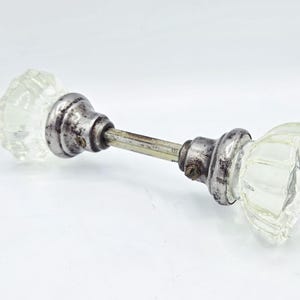 Puede incluir: Pomo de puerta de cristal antiguo con un diseño transparente y facetado. El pomo está unido a una varilla metálica con herrajes envejecidos de color plateado. Un accesorio de puerta vintage.