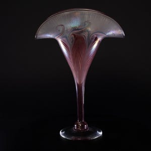 May include: A tall, iridescent glass vase with a wide, flared opening and a slender stem. The vase has a swirling, feathered pattern in shades of purple and pink.
