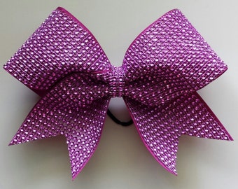 May include: A large, bright pink cheer bow with a sparkly, rhinestone design.